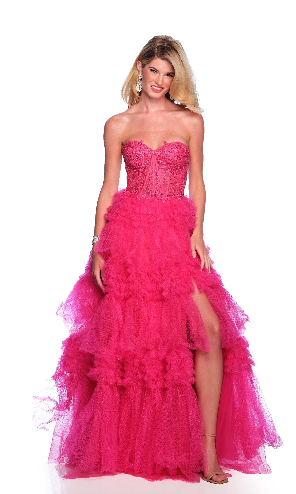 Woman wearing the Fuchsia Pink Prom Ball Gown: Dave & Johnny 11845, featuring a strapless sheer corset bodice, ruffle tulle skirt, and high slit. She stands smiling against a white background.